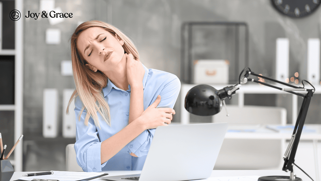 a woman with a neck pain sits in her office using a laptop