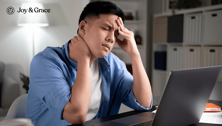 a man sitting at a desk with his laptop while having headaches