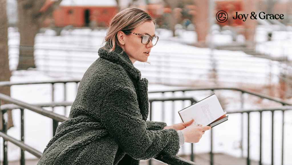 a woman wearing glasses reading a book in snow