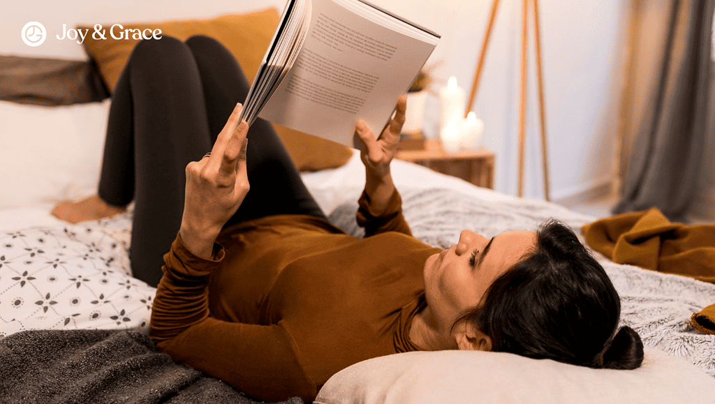 a woman is reading a book while laying on her bed