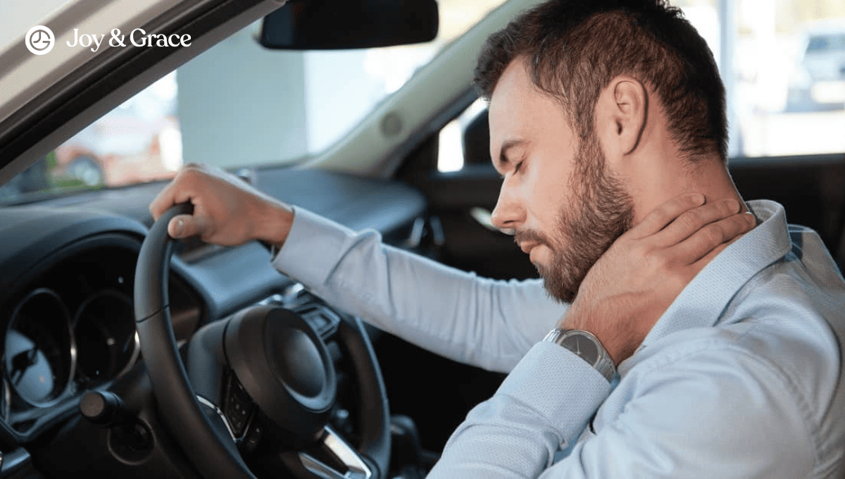 A man in his car rubbing the back of his neck