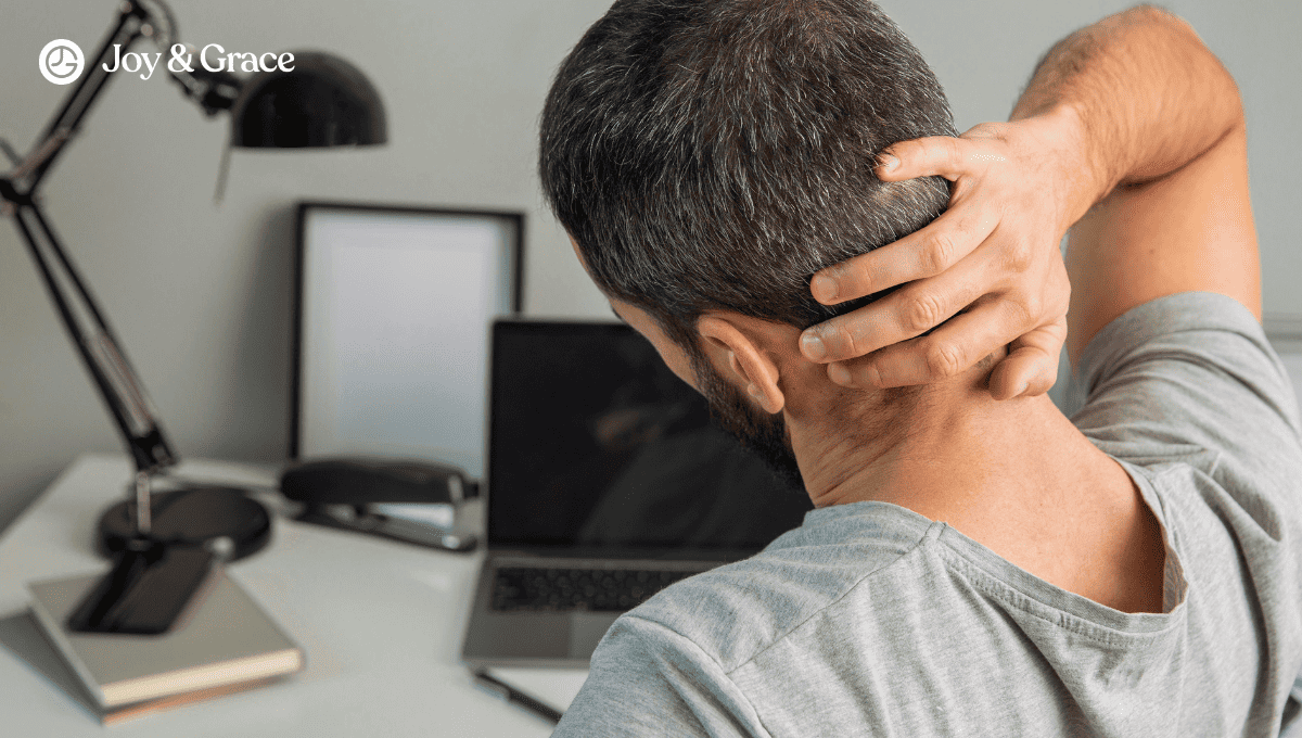 a man sitting in front of his laptop and holding his head