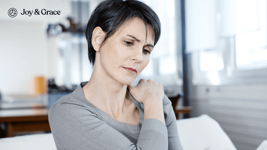 a woman sitting in a couch while holding left shoulder