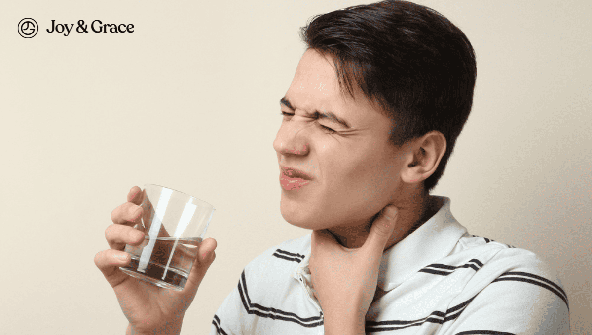 a man holding his throat and drinking from a glass