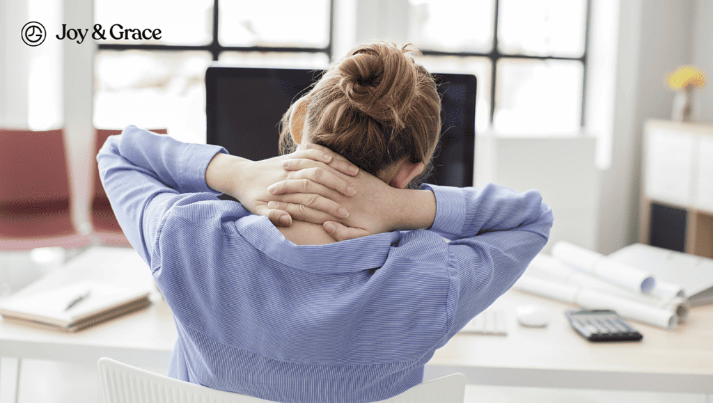 a woman with her hands to her head sits at a computer desk