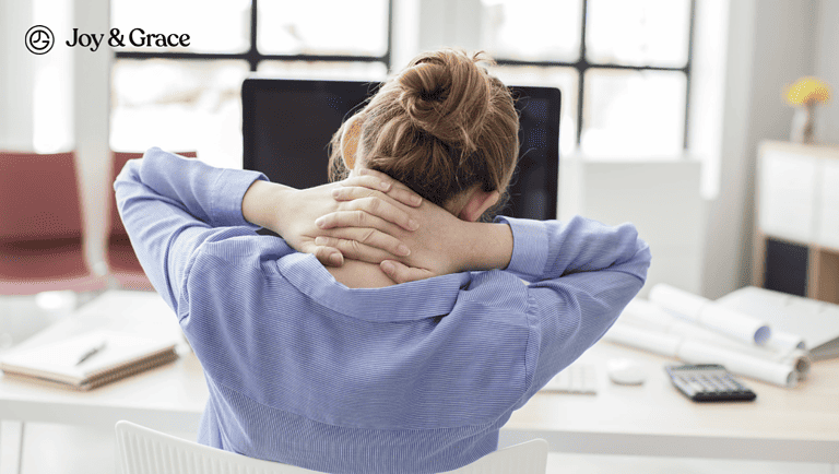 a woman with her hands to her head sits at a computer desk