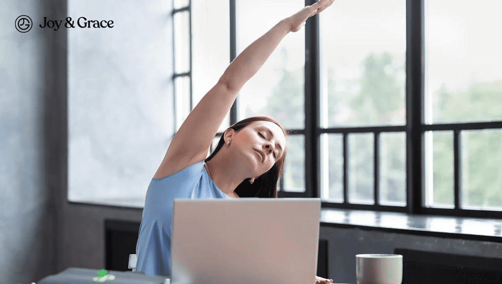 a woman stretches out her arms as she works on a laptop