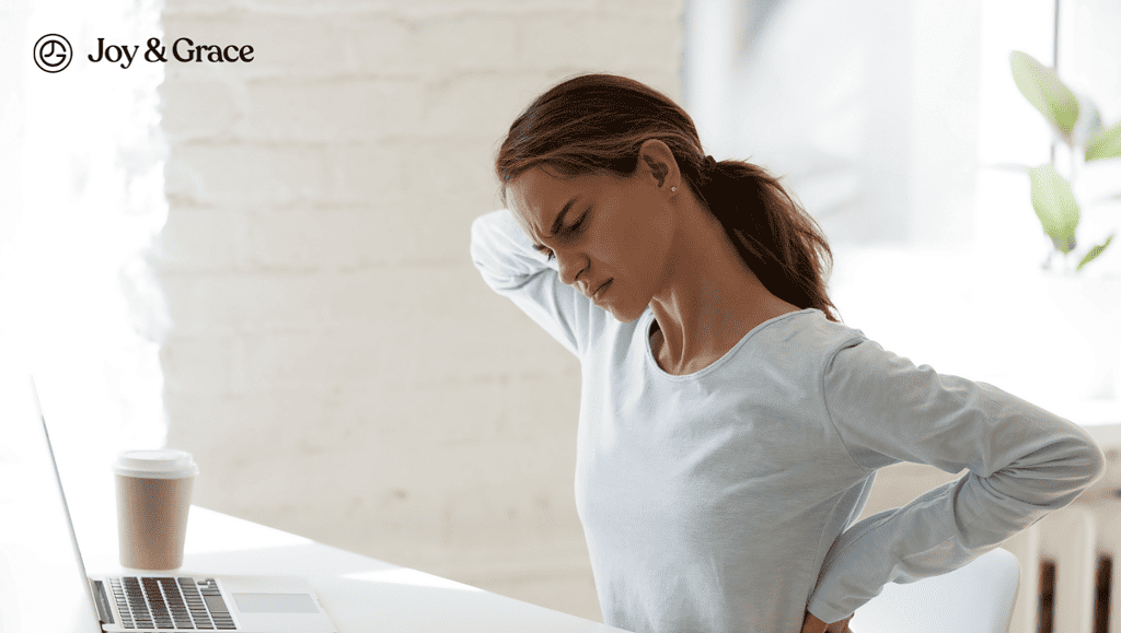 a woman is stretching her back at a table with a laptop computer on it