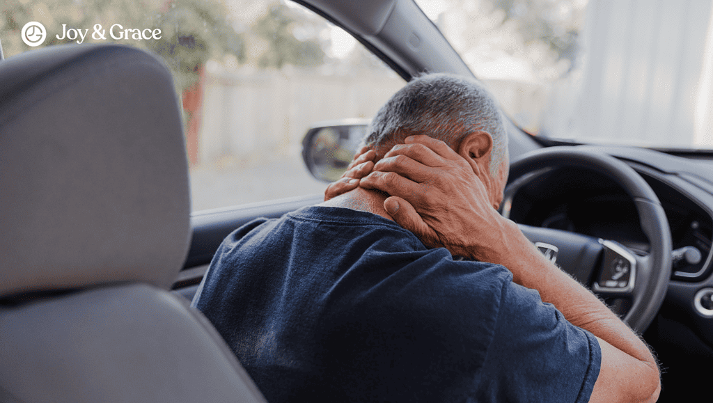 a man in the car seat while holding his neck