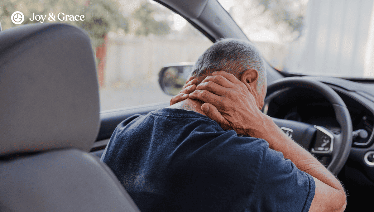 a man in the car seat while holding his neck