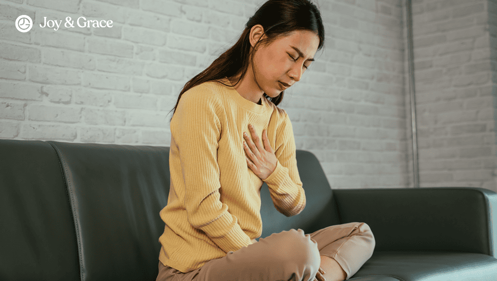 a woman sitting on the couch with her hand on her chest