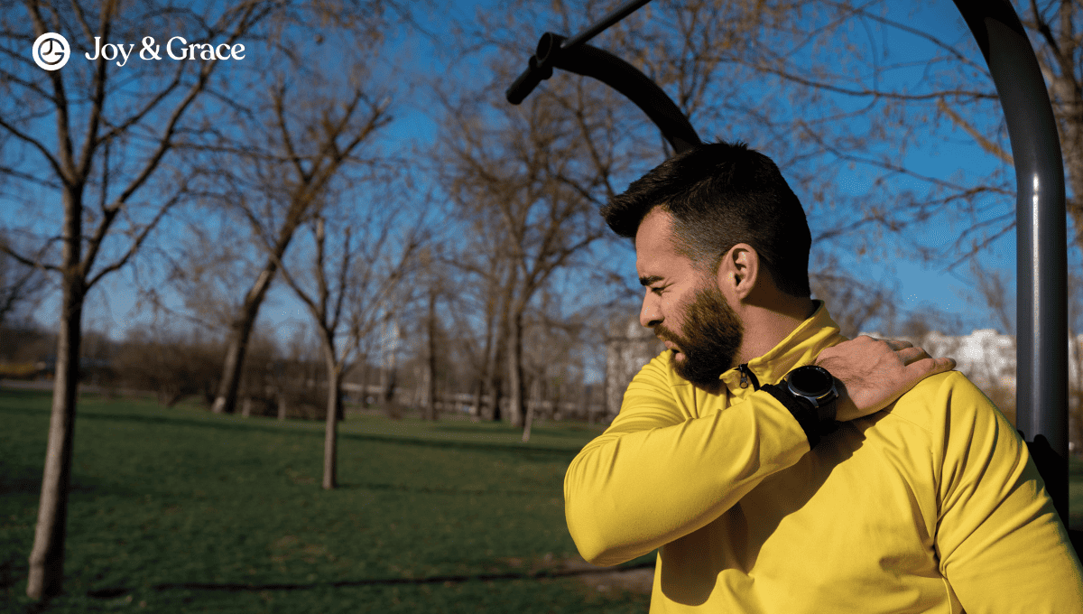 man in a yellow sweater holding up his shoulder