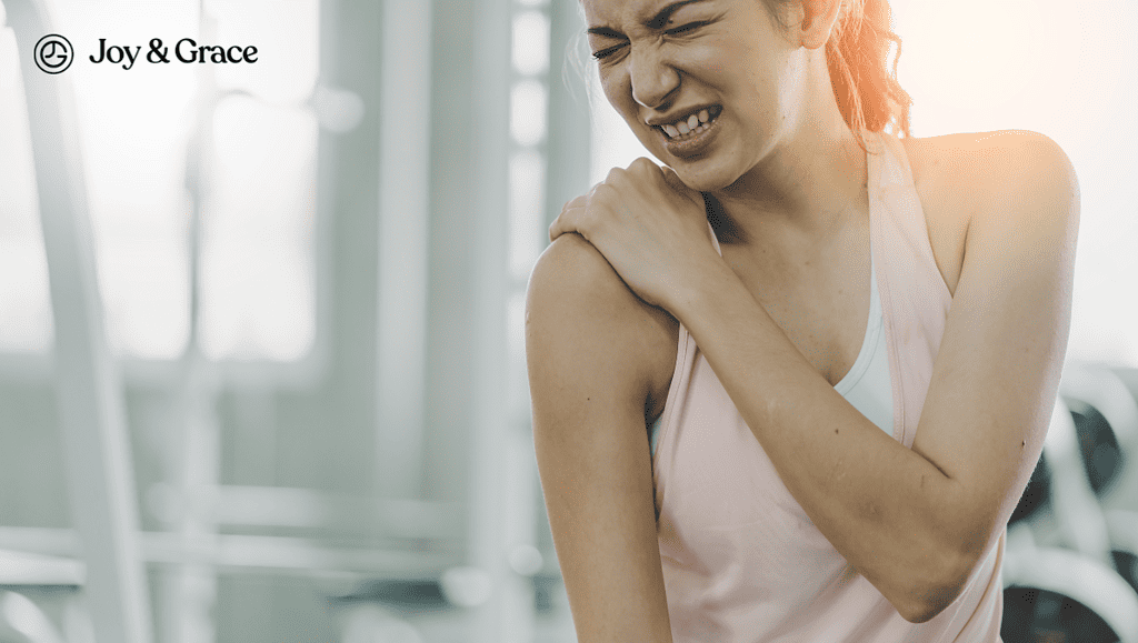 a woman in pain while holding her shoulder