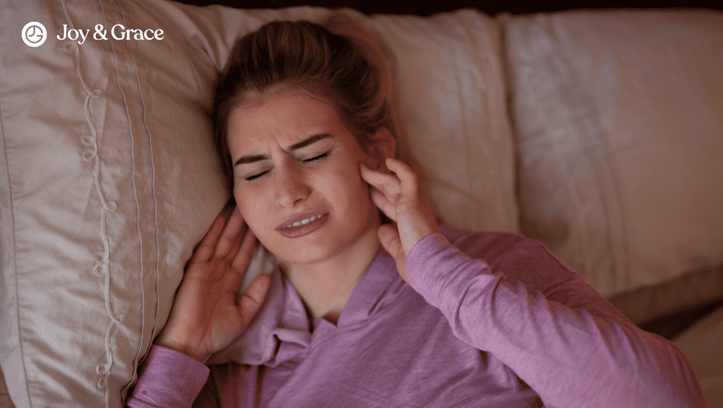 A woman experiencing discomfort from teeth grinding while in bed.