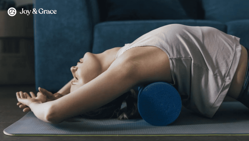 A woman laying on a yoga mat with a blue yoga pillow, alleviating myofascial pain in her shoulder and neck.