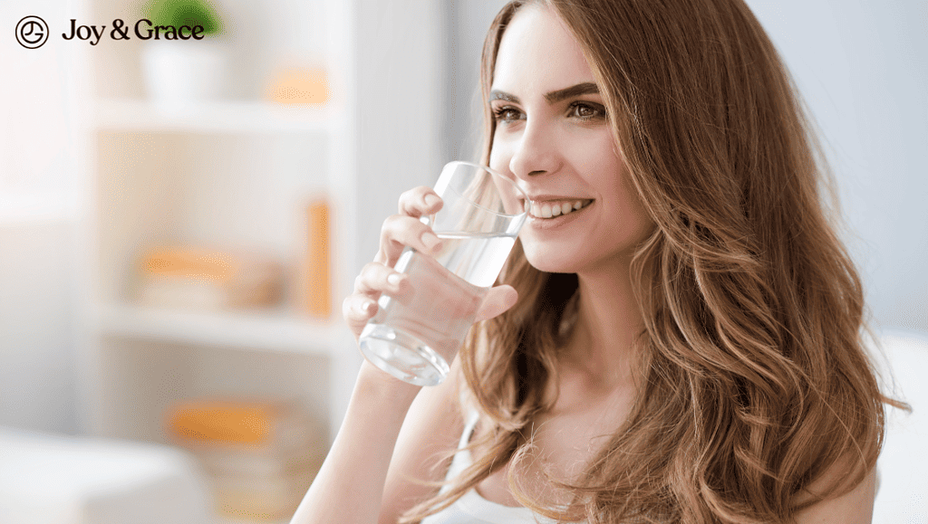 A woman drinking a glass of water for hydration.