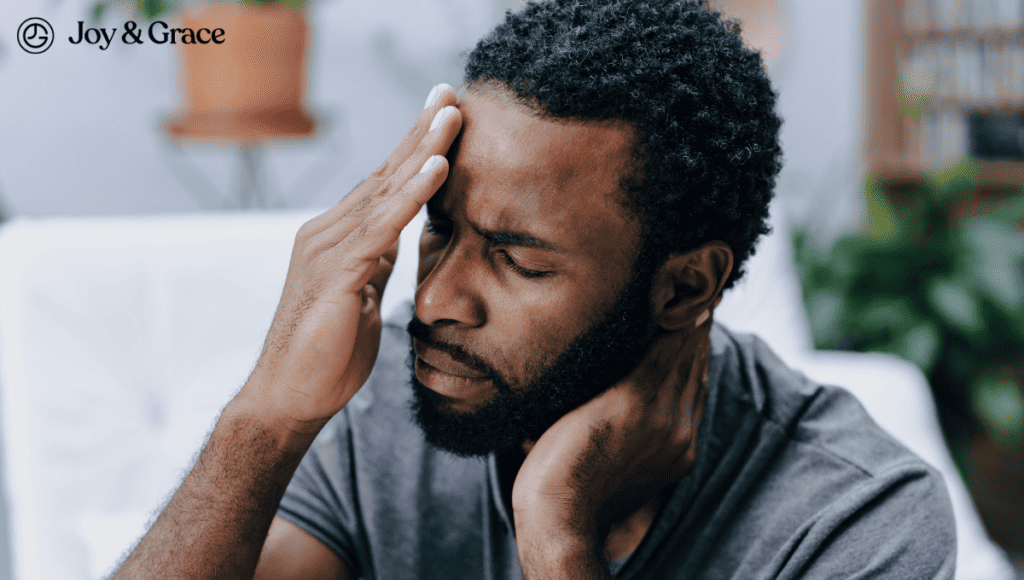 A man is holding his head with his hands, experiencing neck pain.