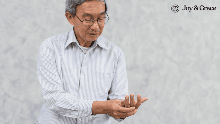 An asian man holding a cell phone in his hand, dealing with shoulder pain.