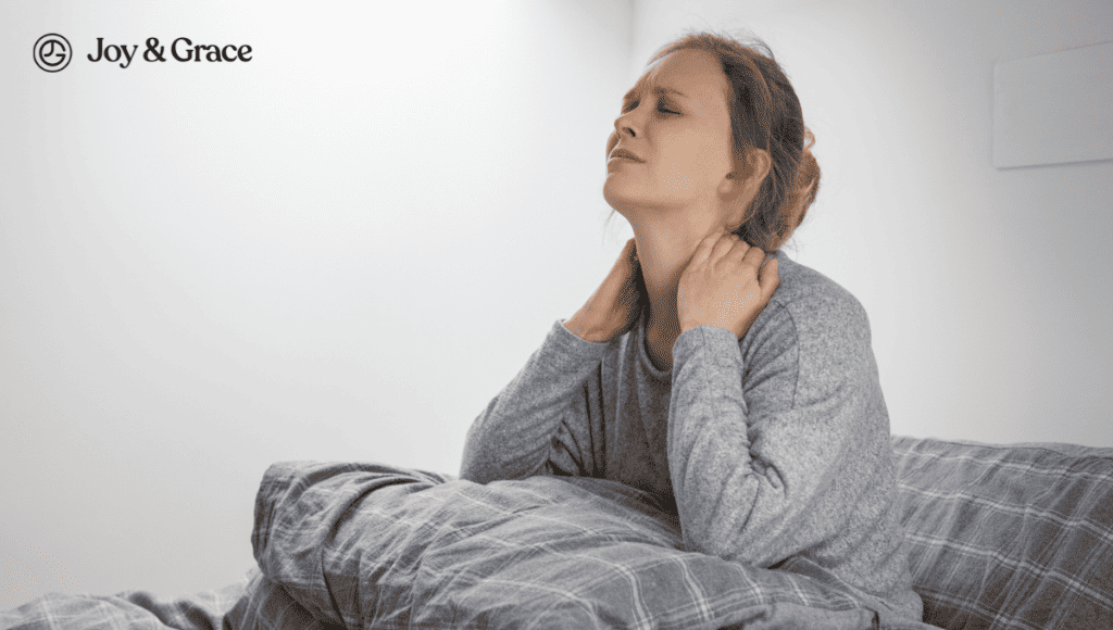 A woman is sitting in bed with a burning pain in her neck and shoulders.