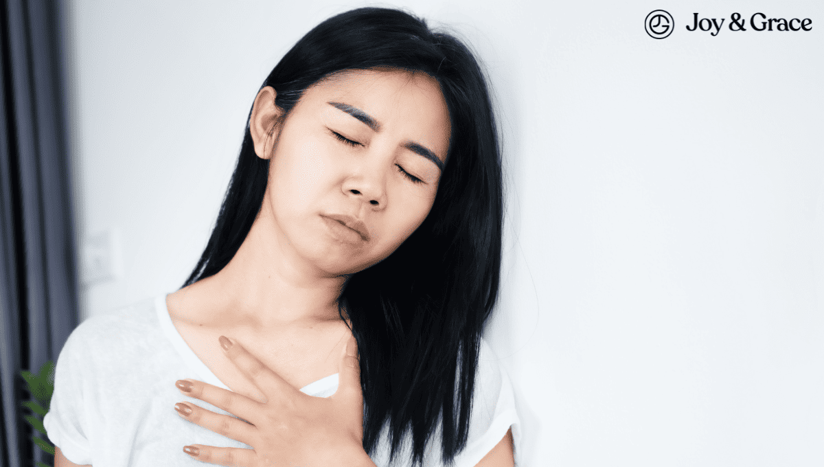 A woman is holding her chest against a wall, experiencing left shoulder pain.