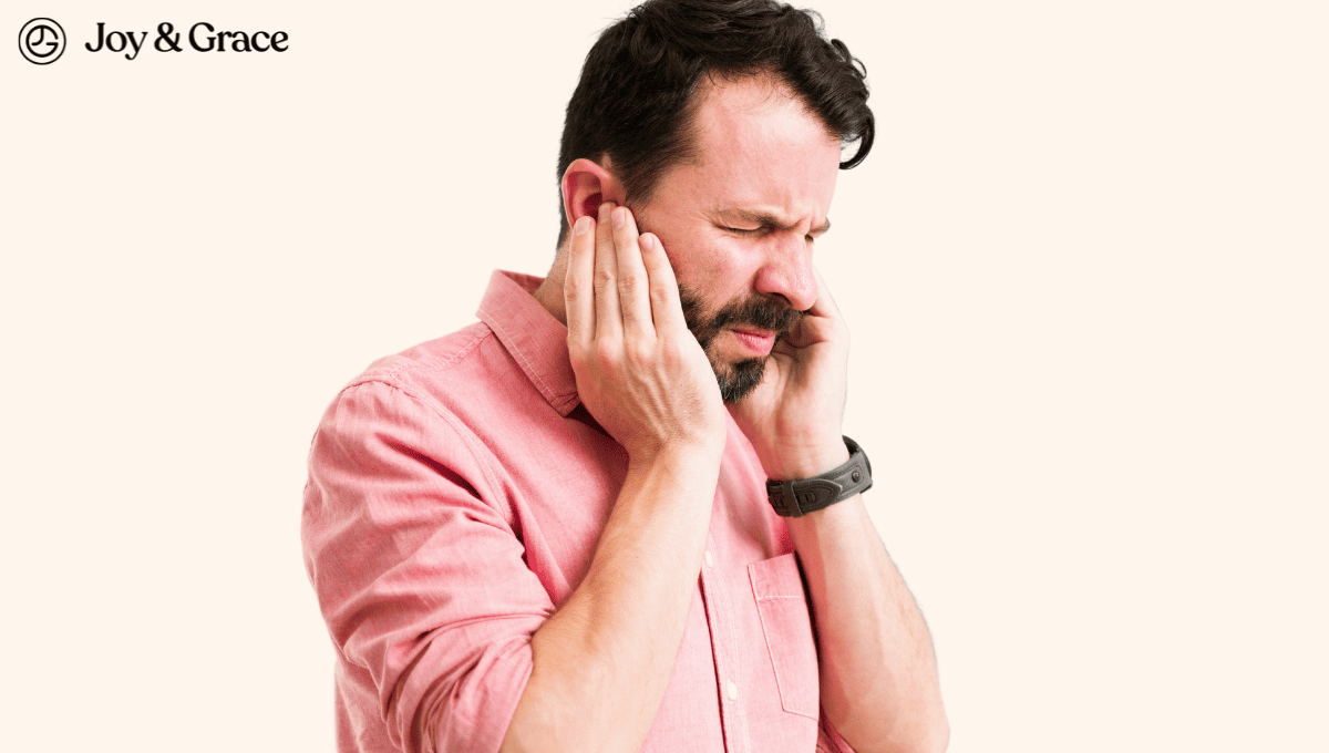 A man is touching his ear with his hand, possibly experiencing ear ringing.