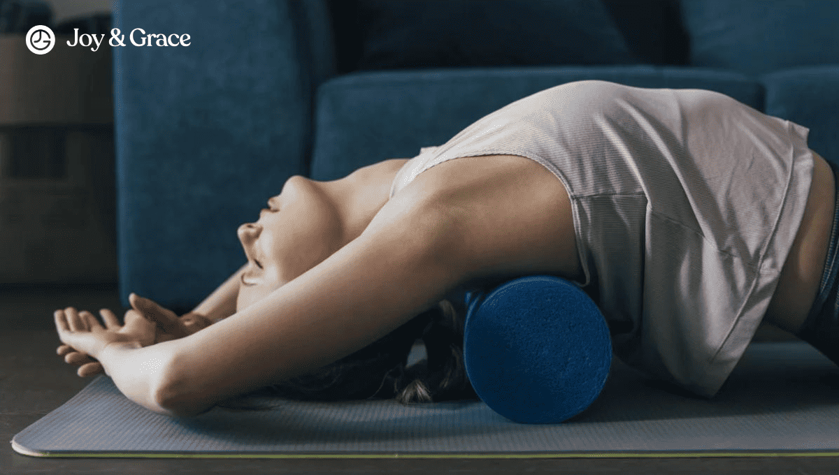 A woman laying on a yoga mat with a blue yoga pillow seeking help for neck and shoulder pain.