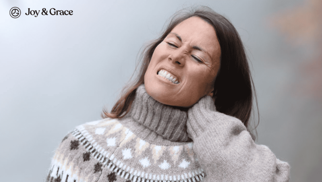 A woman with neck pain resulting from a cold, wearing a sweater.