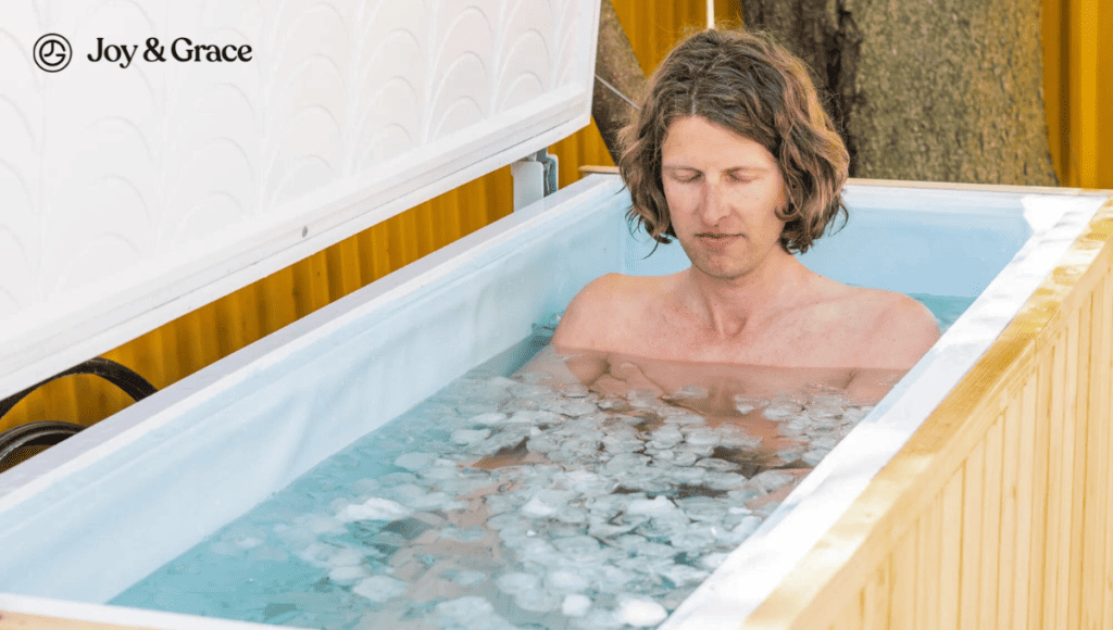 A man is sitting in a hot tub filled with ice cubes, seeking relief for his shoulder pain.