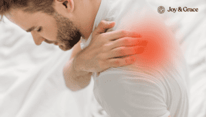 A man experiencing sharp pain in the back of his left shoulder while lying in bed.