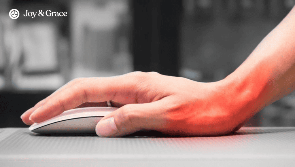 A person's hand on a computer mouse with a red light on it, causing discomfort in their left shoulder.