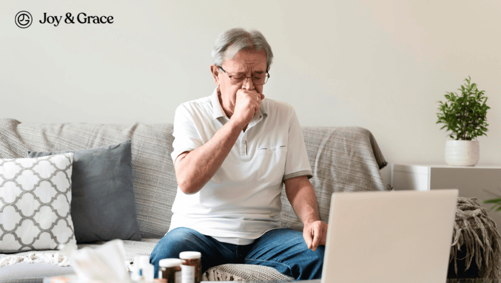 A man sitting on a couch with a laptop and bottle of cough medicine.