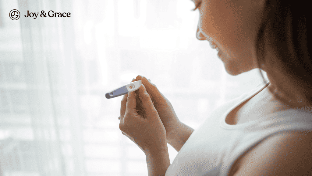 A woman experiencing shoulder pain holds a blood test in front of a window, possibly indicating an ectopic pregnancy.